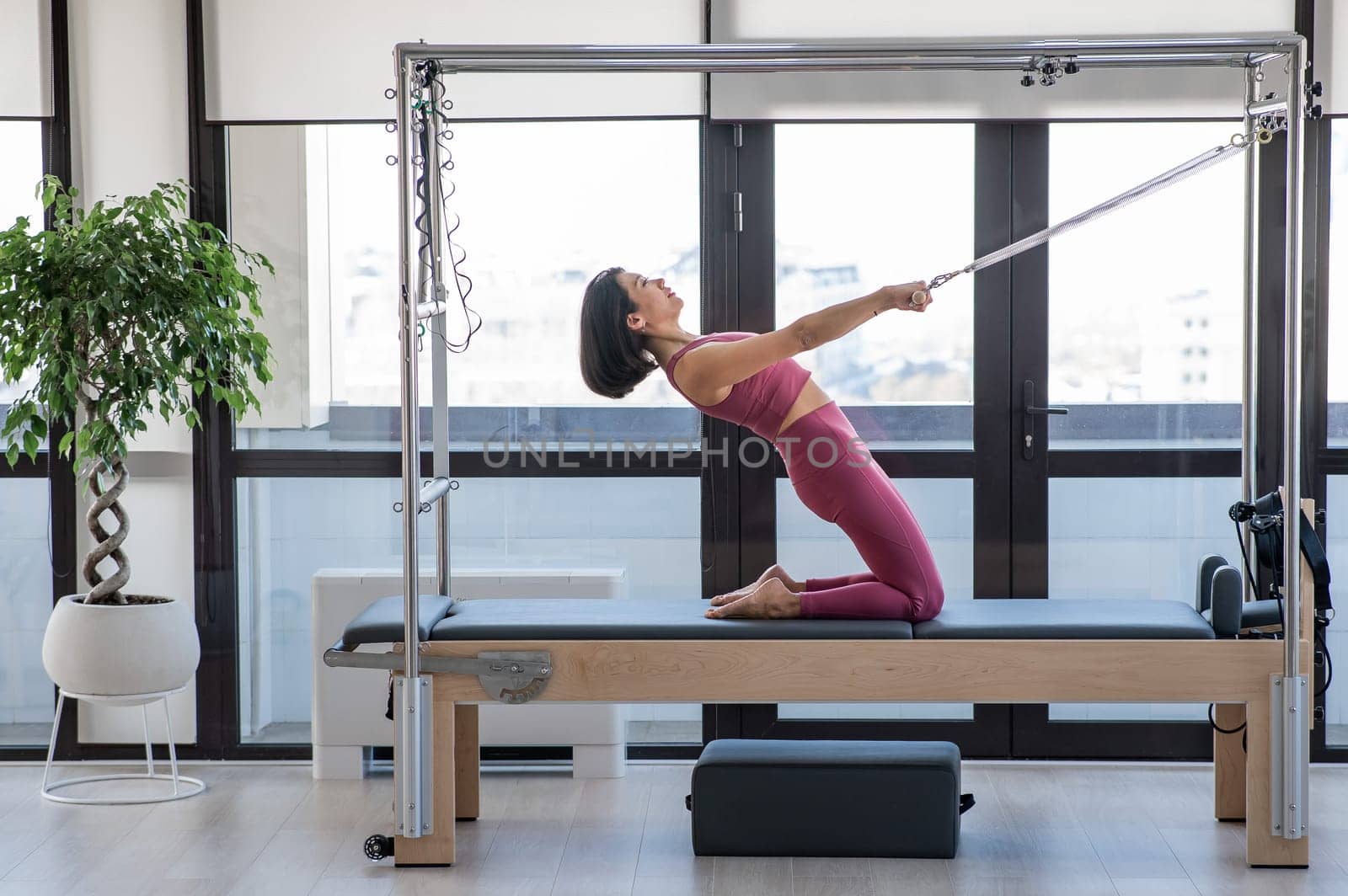 Asian woman doing Pilates on reformer machine