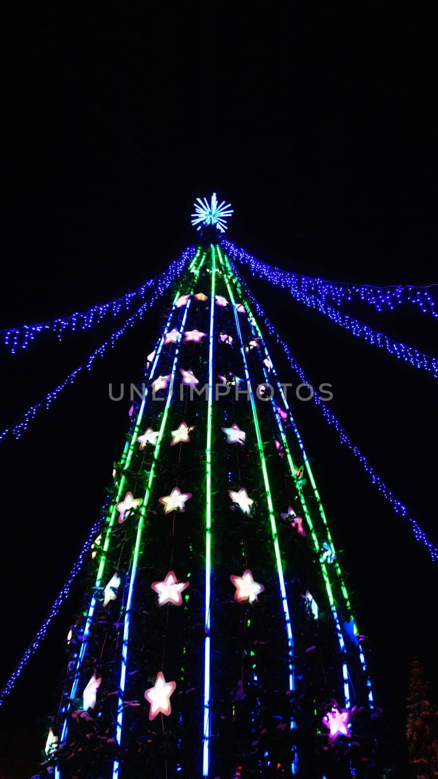 Festive Christmas Tree Decorated With Colorful Ornaments On A Black Background. Vertical photo