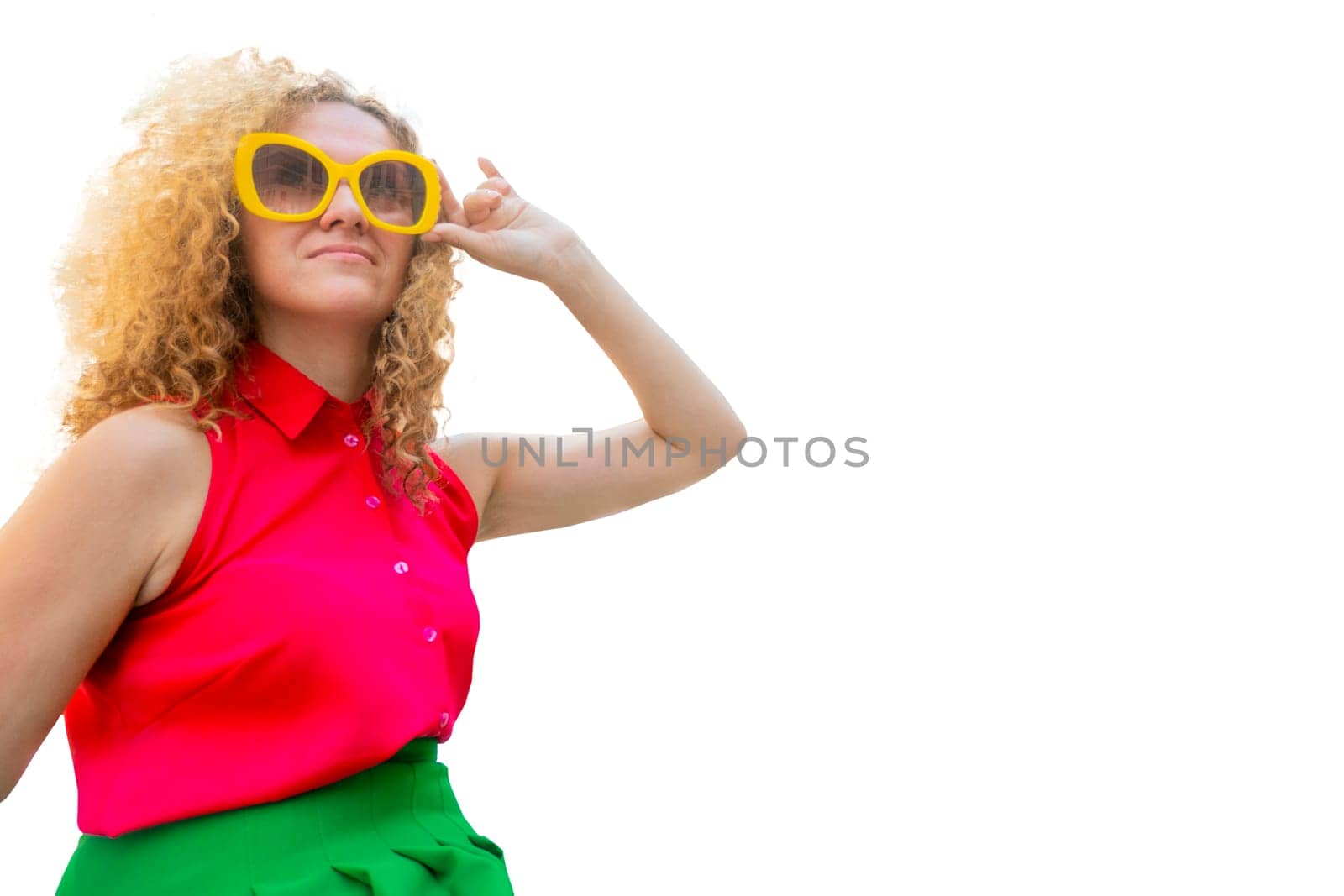 Young blonde woman with long curly hair in red and green fashion closes in sun glasses playful smile happy positive adjusts his glasses