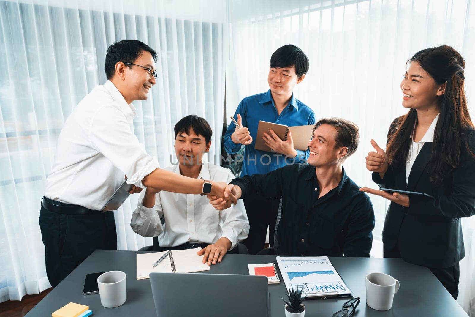 Diverse group of office employee worker shake hand after making agreement on strategic business marketing meeting. Teamwork and positive attitude create productive and supportive workplace. Prudent