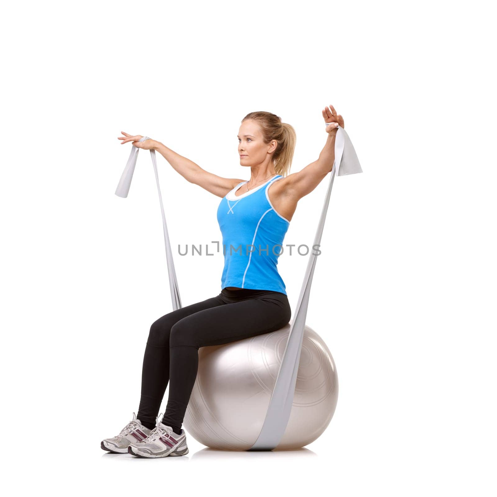 Yoga ball, resistance band and woman doing exercise in studio for health, wellness and body care. Sports, fitness and young female person from Canada with arms workout or training by white background by YuriArcurs