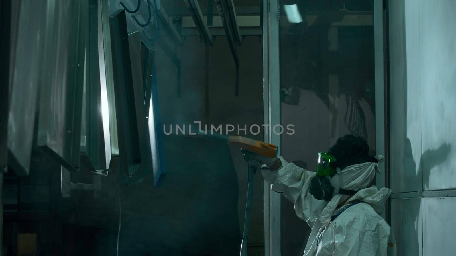 Male technician air-painting metal details at industrial plant. Creative. Industrial spray painting process