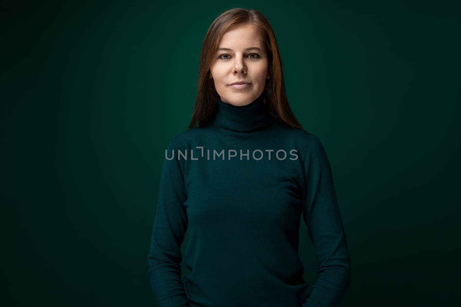 Portrait of a well-groomed young woman with brown eyes on a dark green background by TRMK