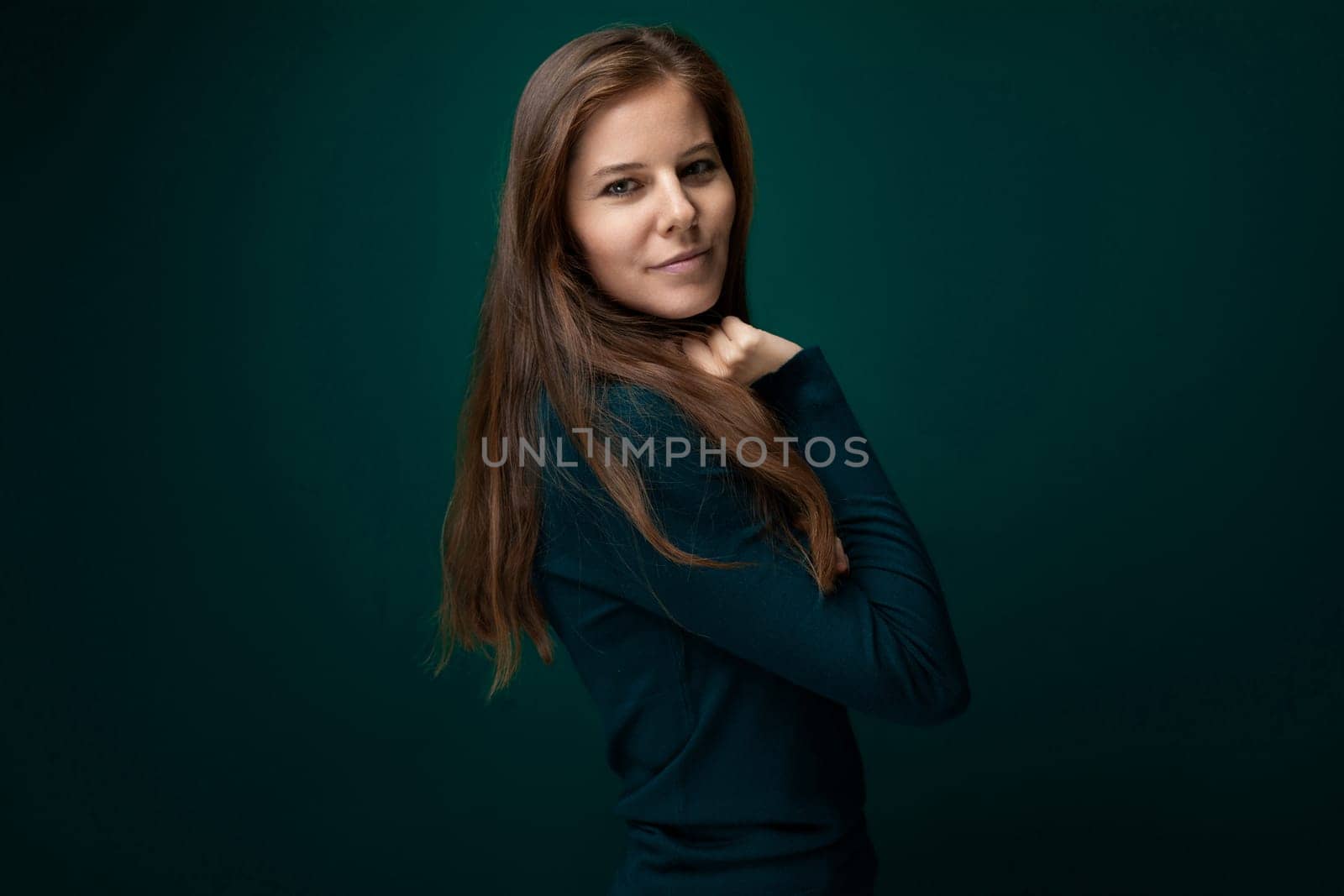Caucasian young woman wearing a green turtleneck on a dark background with copy space.
