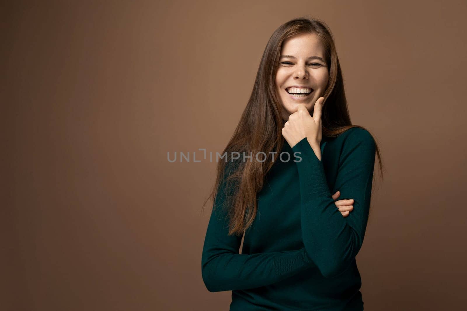 Attractive young woman with healthy brown hair on a brown background with copy space.