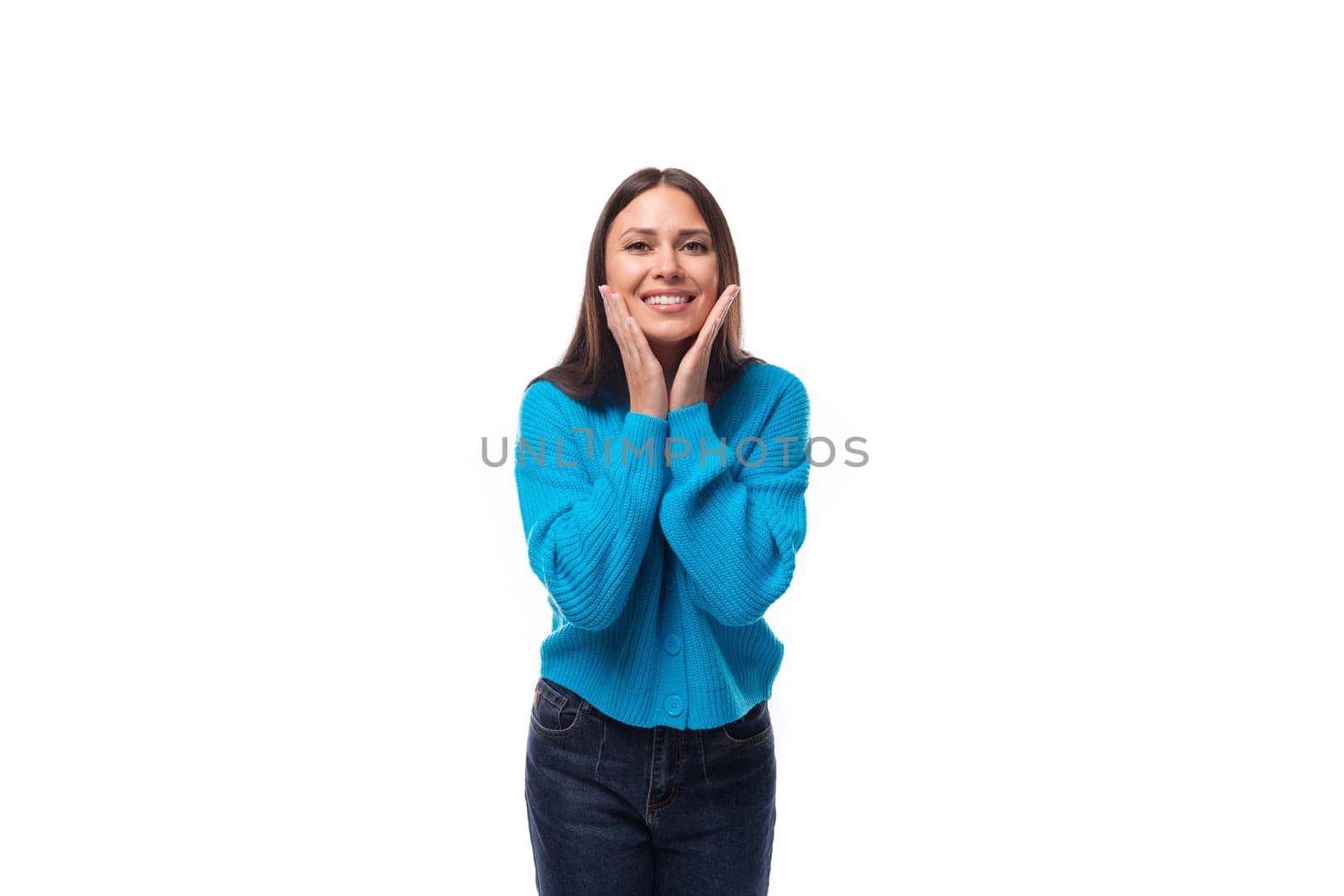 portrait of a young slender brunette woman with light makeup dressed in a blue sweater and jeans on a white background by TRMK
