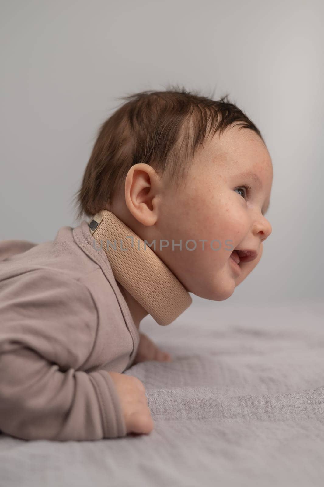 Portrait of a newborn baby lying on his stomach in an orthopedic collar. Vertical photo