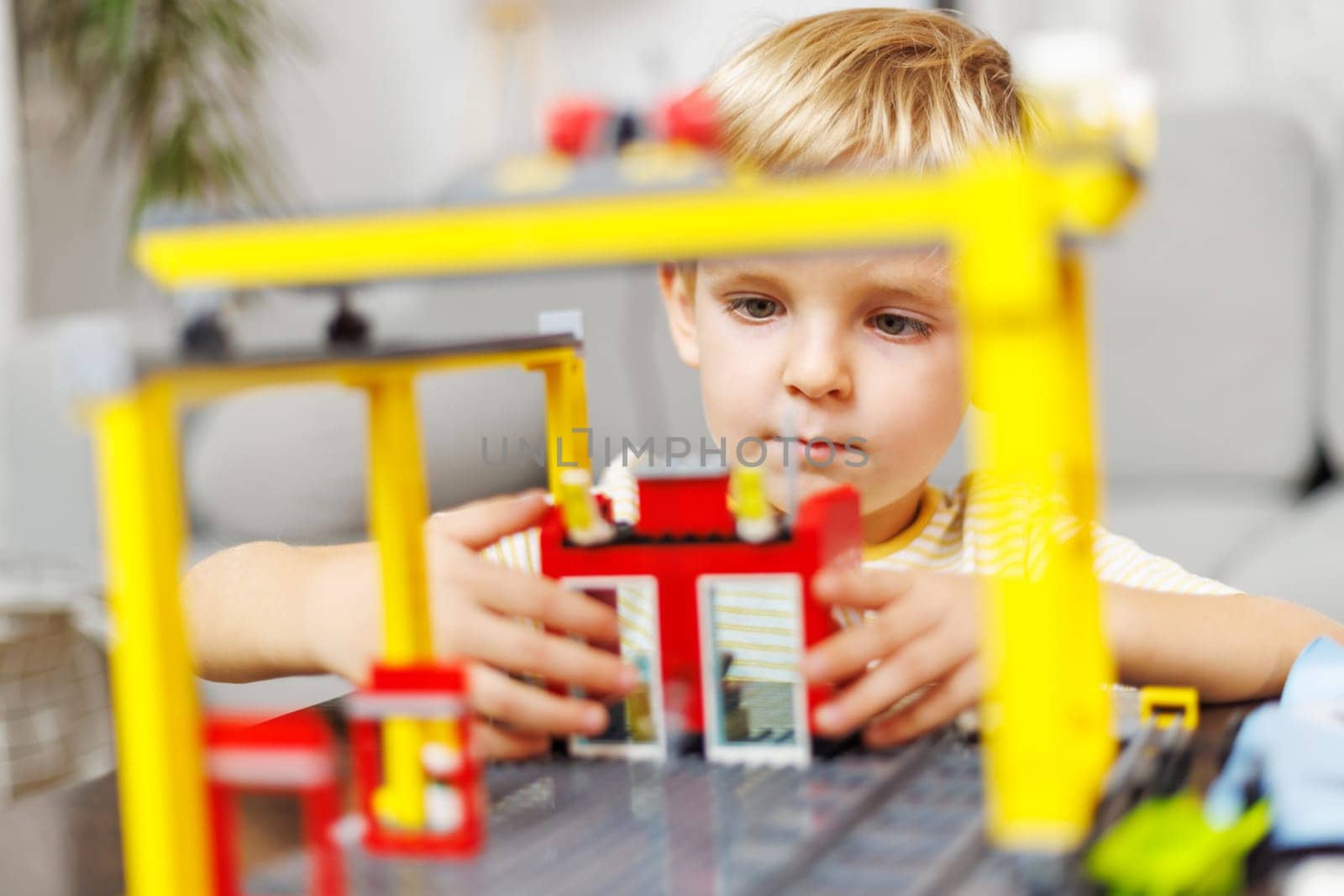 Child boy playing and building with colorful plastic bricks at the table. Early learning and development