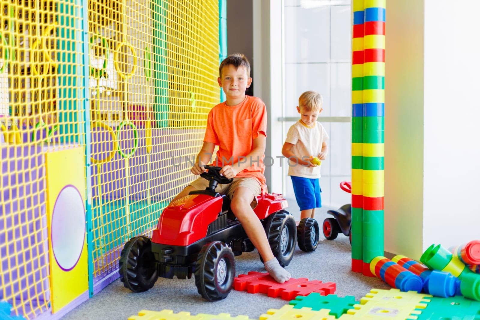 A child rides a toy pedal car at a children's play center.