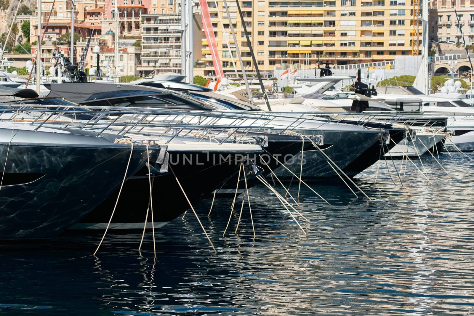 Sun glare on glossy board boats, azure water, tranquillity in port Hercules, bows of moored boats at sunny day, megayachts, Monaco, Monte-Carlo. High quality photo