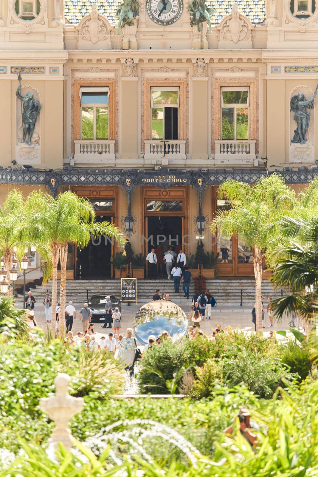 Monaco, Monte-Carlo, 28 September 2022 - Square Casino Monte-Carlo at sunny day, wealth life, tourists take pictures of the landmark, pine trees, blue sky. High quality photo