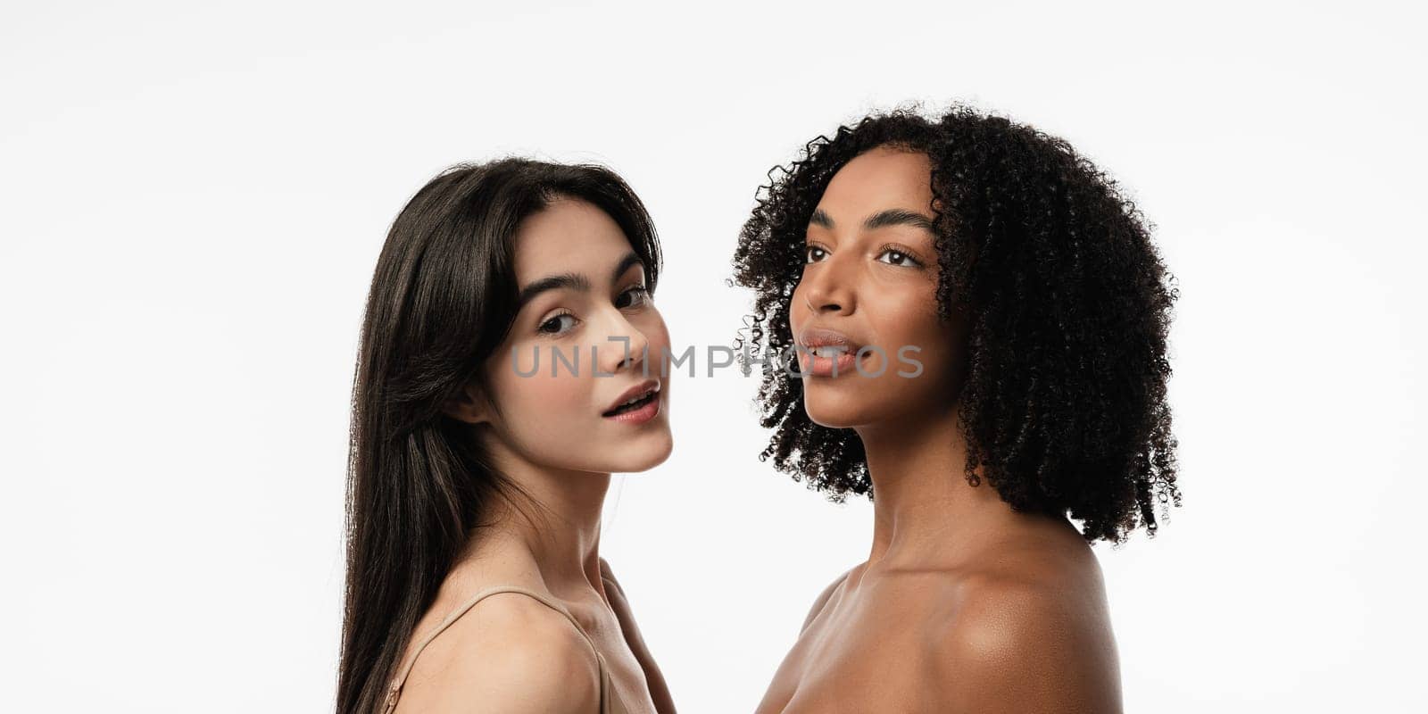 Female models of various ages celebrating their natural bodies in a studio. Two confident and joyful women smiling radiantly, having used cosmetics.