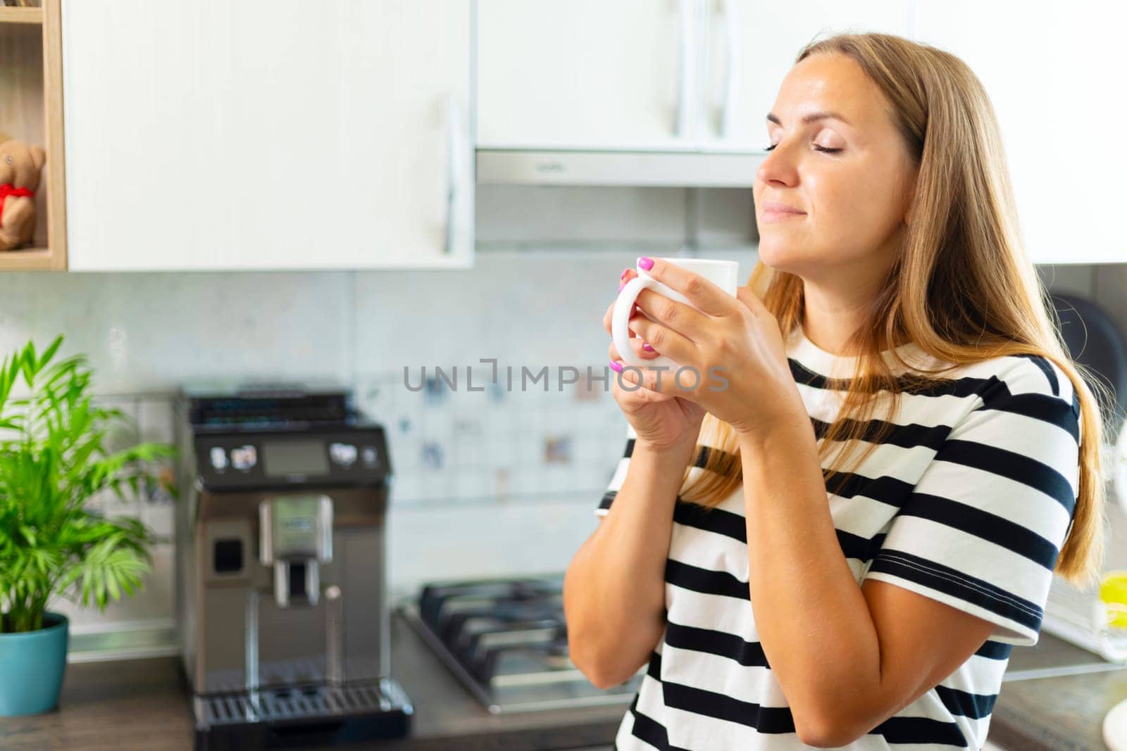 Attractive woman enjoying freshly made coffee in the kitchen in the morning.