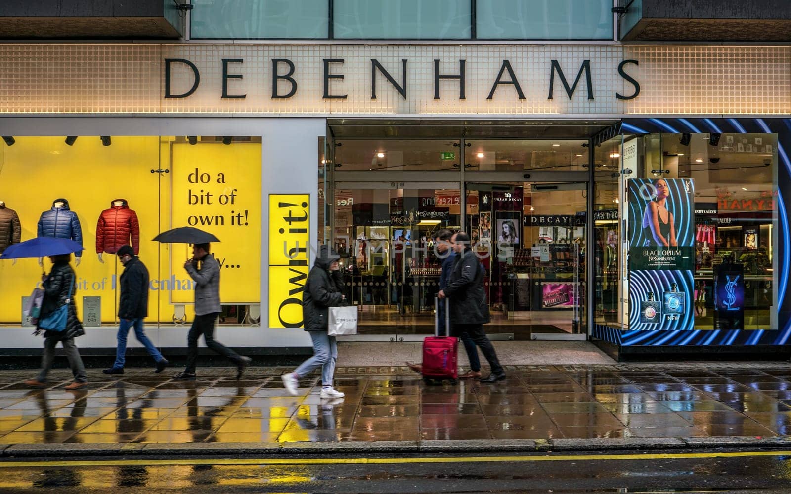 London, United Kingdom - February 01, 2019: People walks in front of Debenhams store Oxford Street branch on a rainy day. British multinational retailer was formed in 1778.