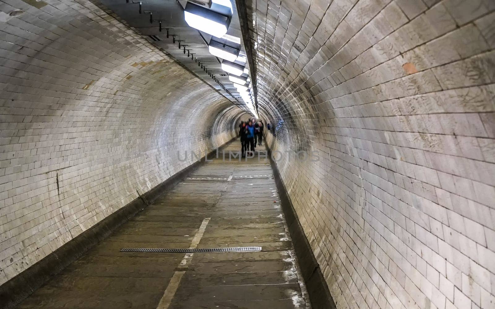 Wide angle photo of Greenwich foot tunnel under river Thames in London, blurred pedestrians in distance by Ivanko