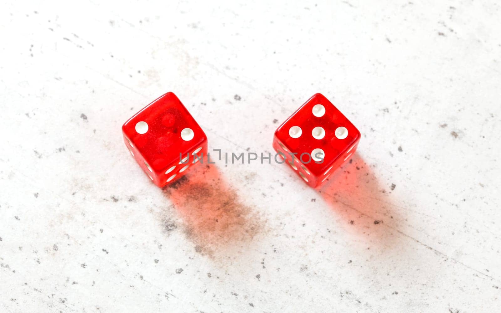 Two red craps dices showing Natural or Seven Out (number two and five) overhead shot on white board by Ivanko