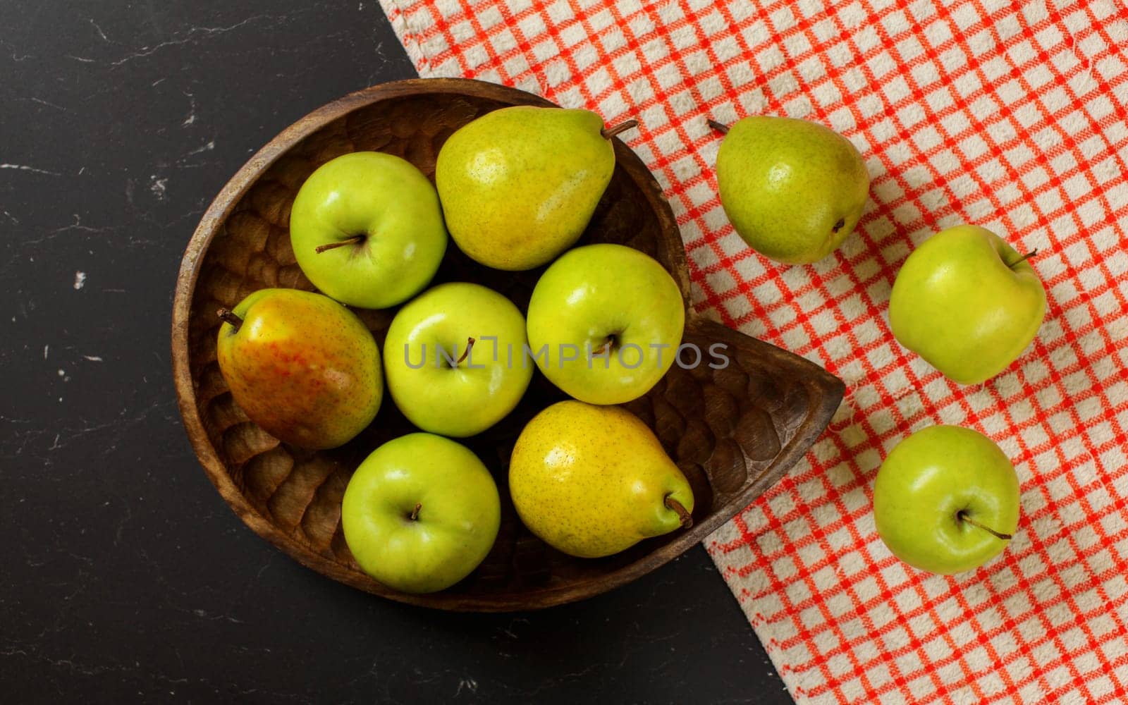 Flat lay photo - vintage wood carved bowl with apples and pears, red chequered tablecloth on black board by Ivanko