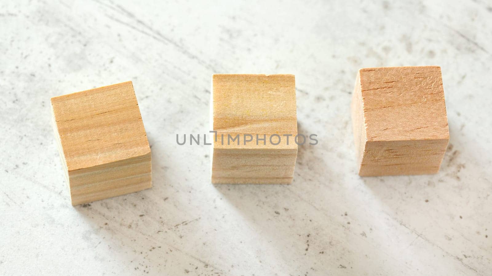 Three empty light wood playing cubes on white board