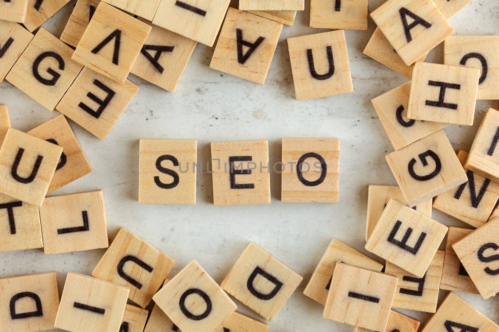 Top down view, pile of square wooden blocks with letters SEO (stands for Search Engine Optimization) on white board. 