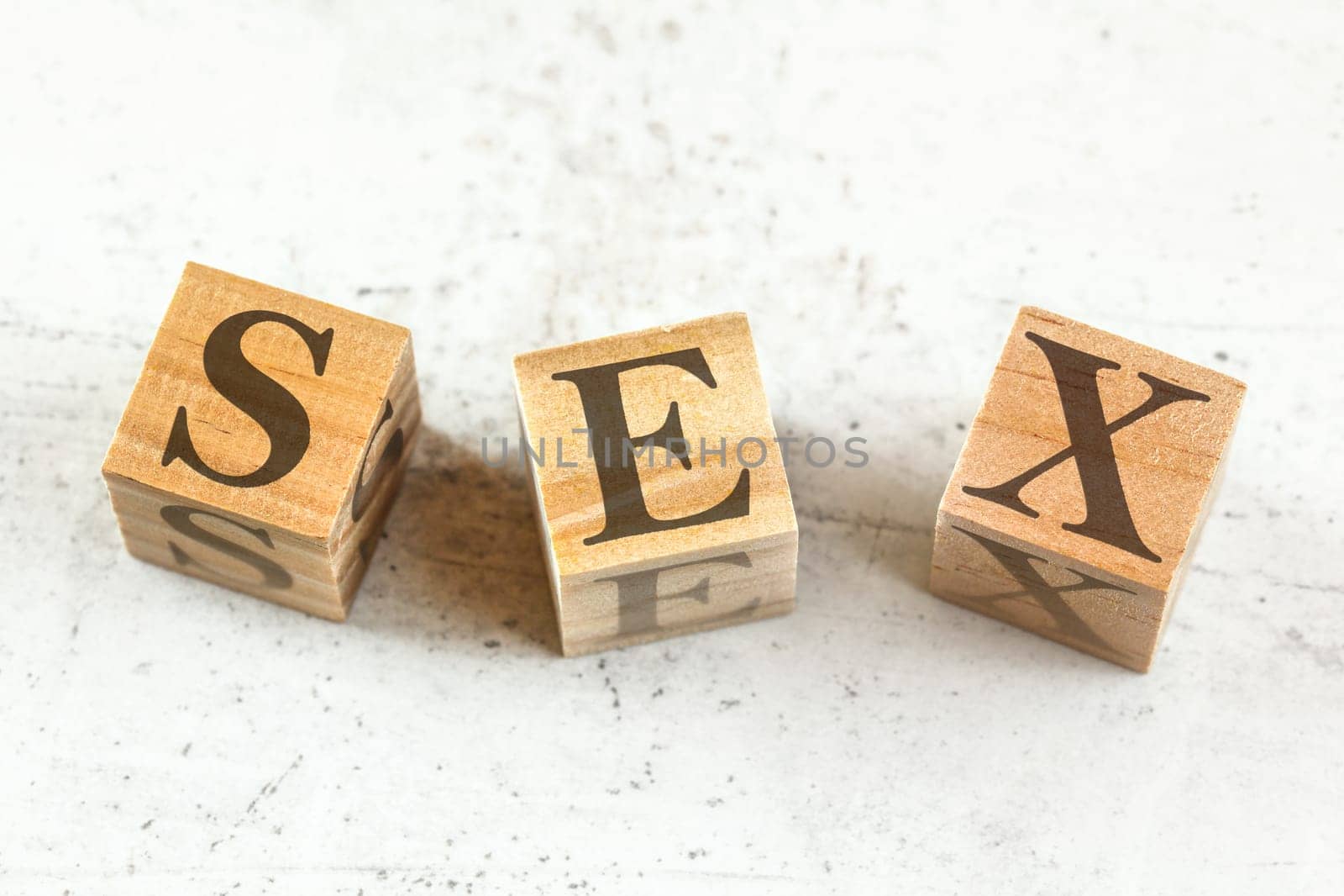 Three wooden cubes with word SEX on white board.