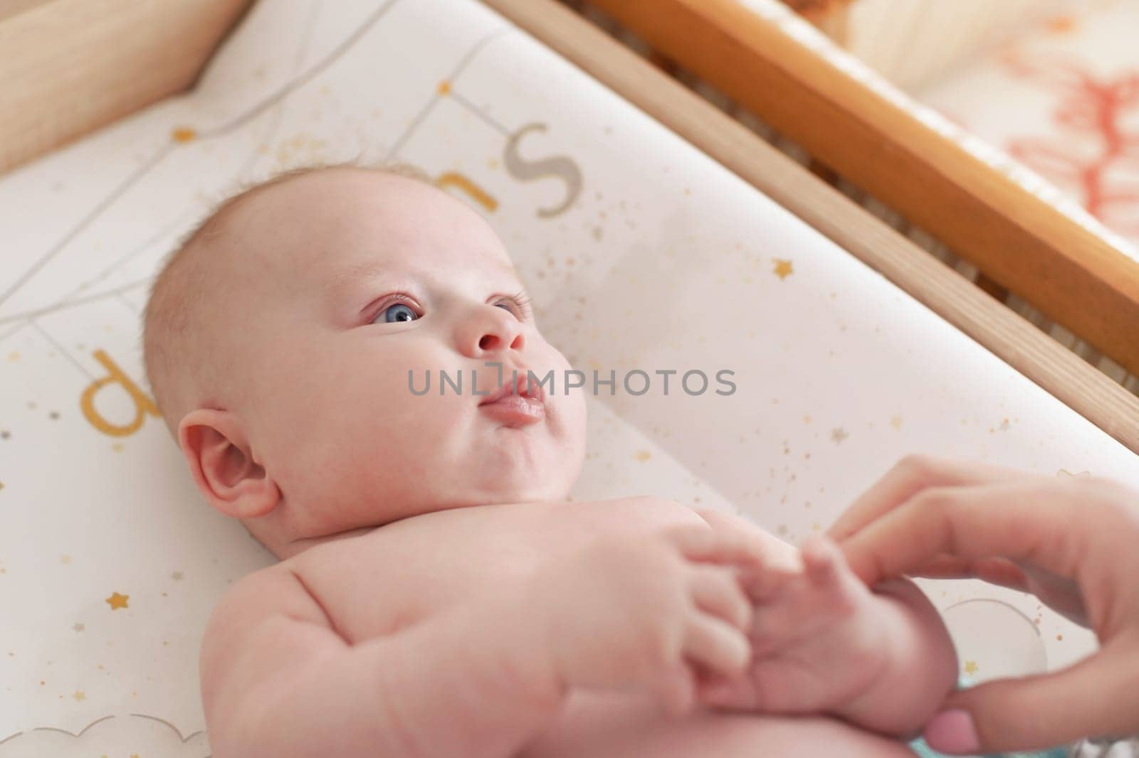 Photo of 3 months old infant baby boy, changing after bath, blurred mother hands in corner