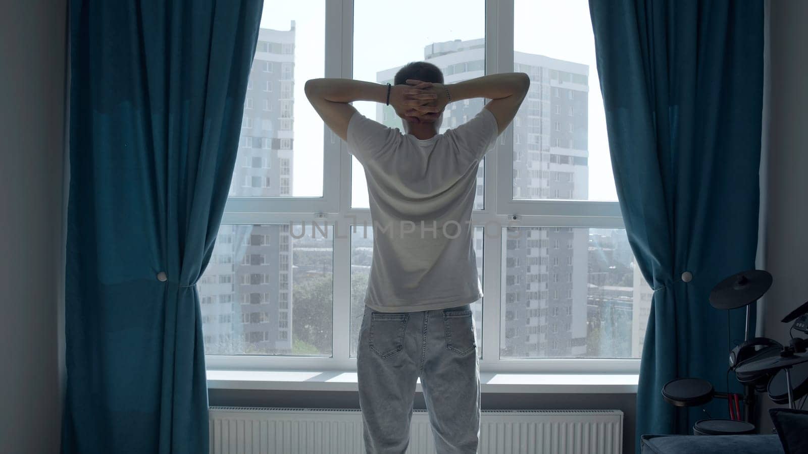 A person engaged in sports. Media. A light background with a large window that stands opposite and does exercises. High quality 4k footage