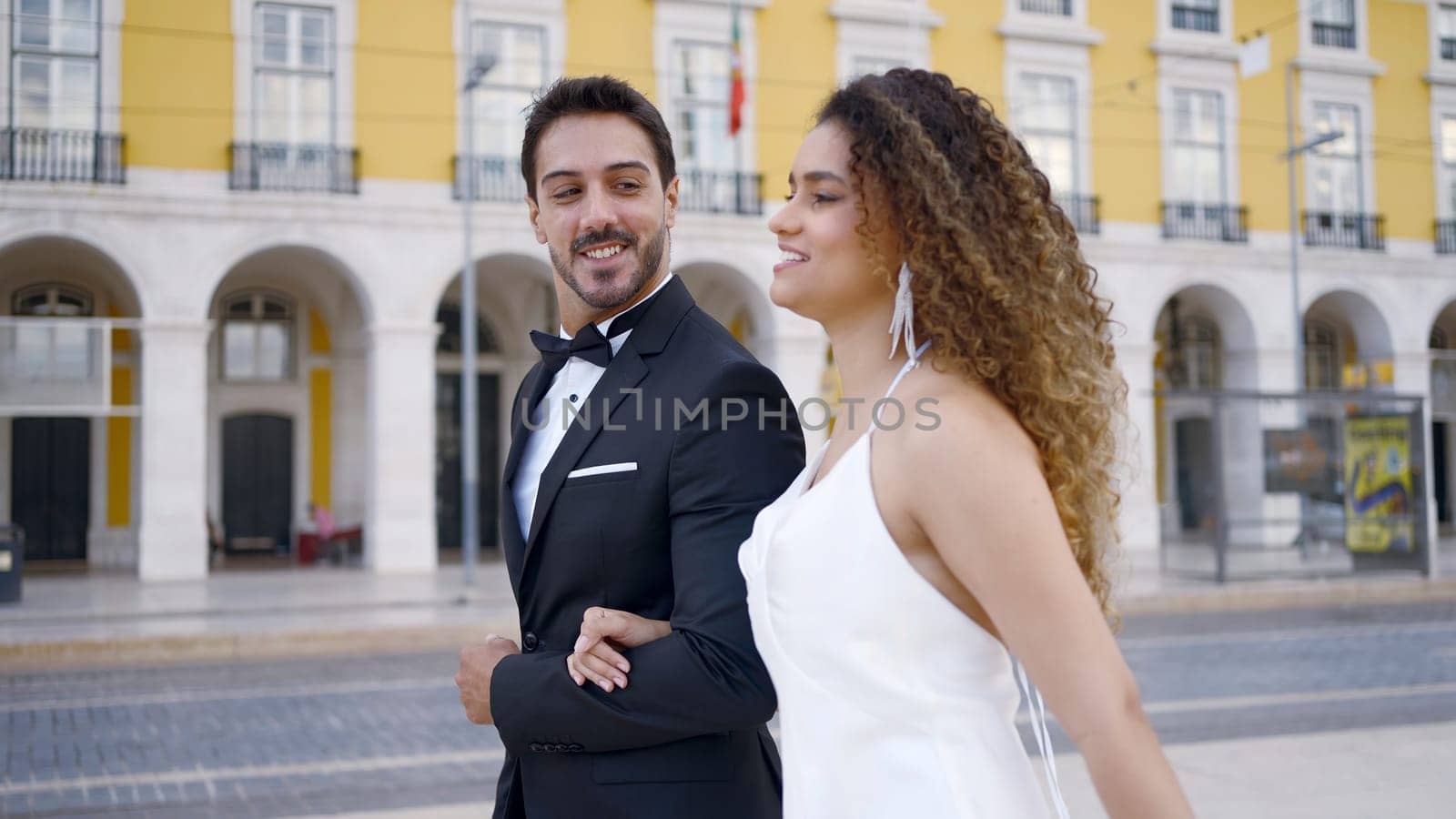 Elegant couple in love walks around city. Action. Gorgeous young couple walks around European city. Beautiful fun walking in stylish outfits around city on sunny summer day. Love story.