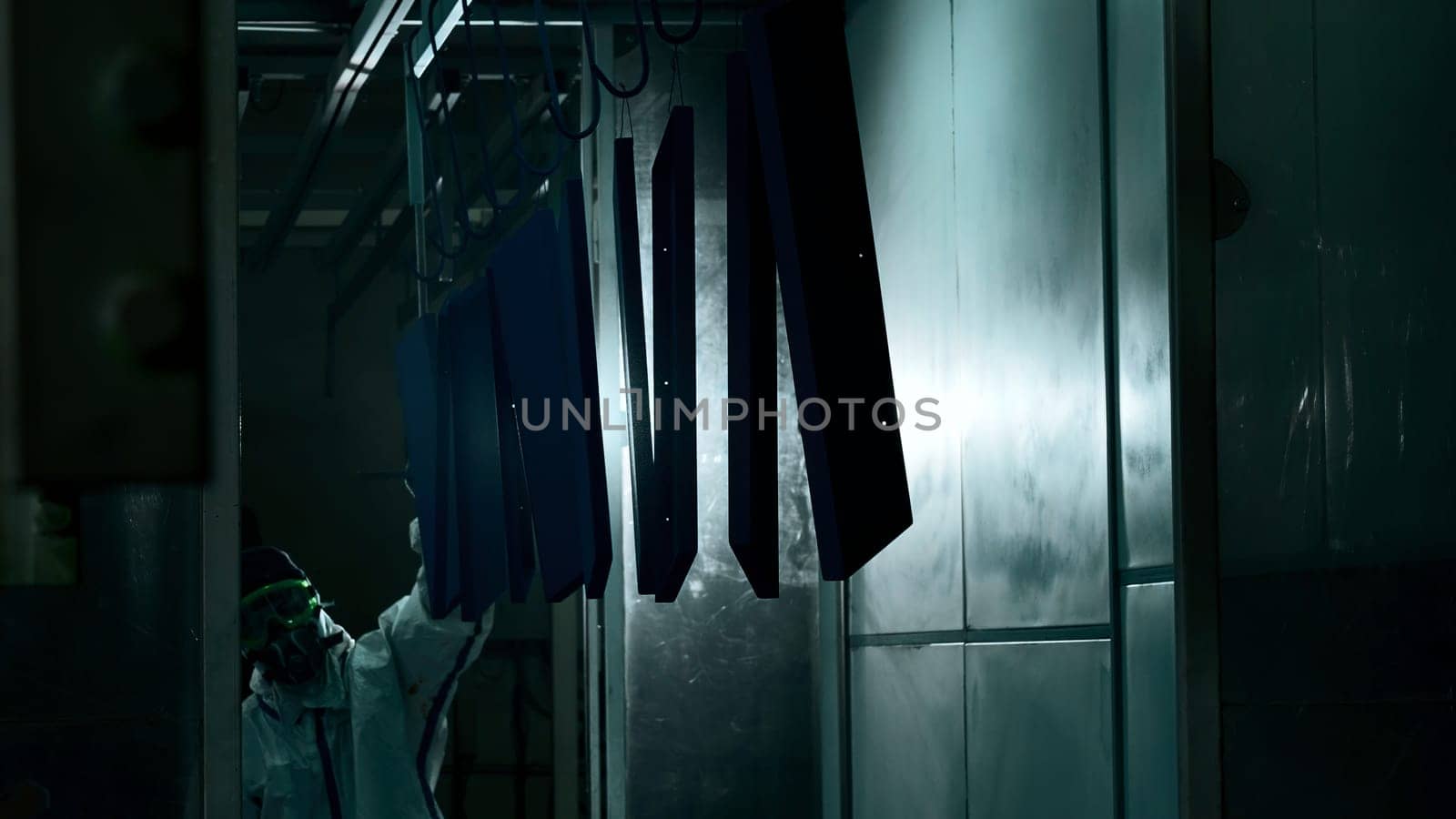 Worker at a factory moving a line of metal sheets. Creative. Man in suit using a steel stick to push the pipe with sheets