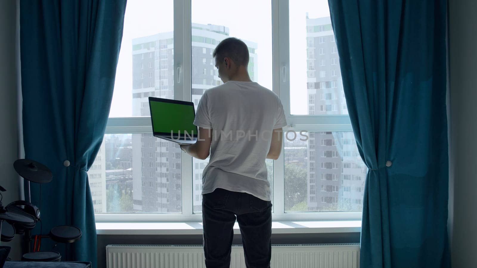 The screen in the laptop is green. Media. A man picking at a laptop with a green screen in front of a light window