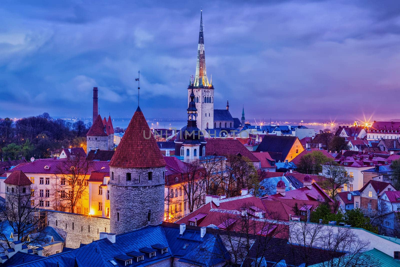 Aerial view of Tallinn Medieval Old Town with St. Olaf's Church and Tallinn City Wall illuminated in evening, Estonia