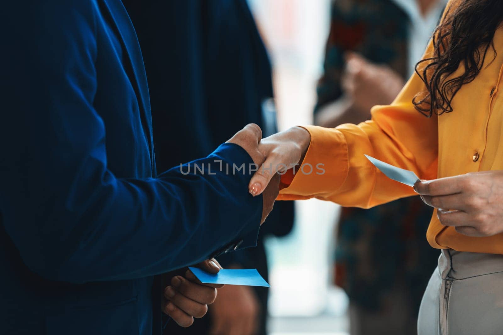 Businessmen shaking hand and making a contract in the sign of agreement, cooperation with businesswoman. Cropped image of managers holding business cards. Their partners standing behind. Intellectual.