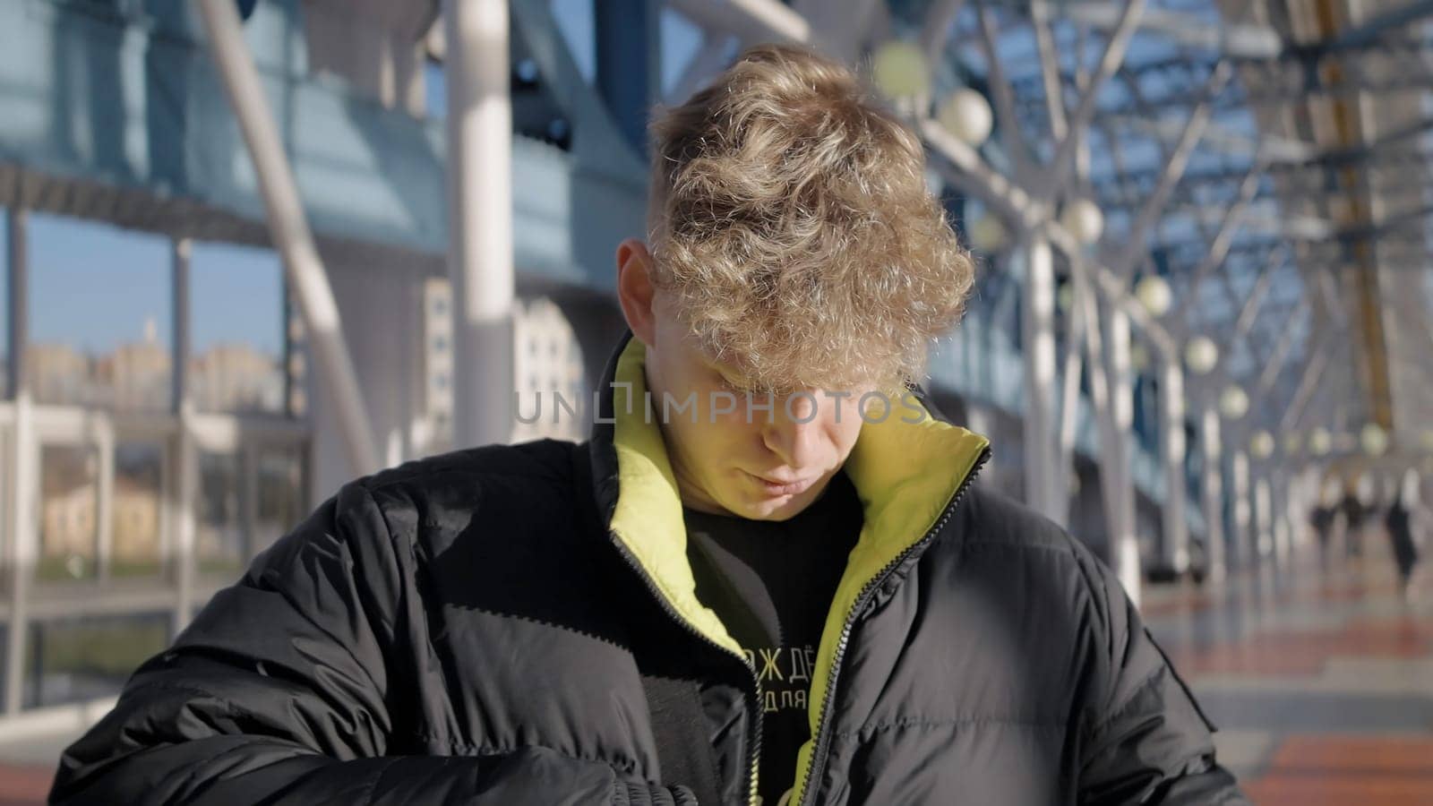 A handsome man in warm clothes. Action. A handsome man with long hair in a jacket walks around the city and the mall. High quality 4k footage