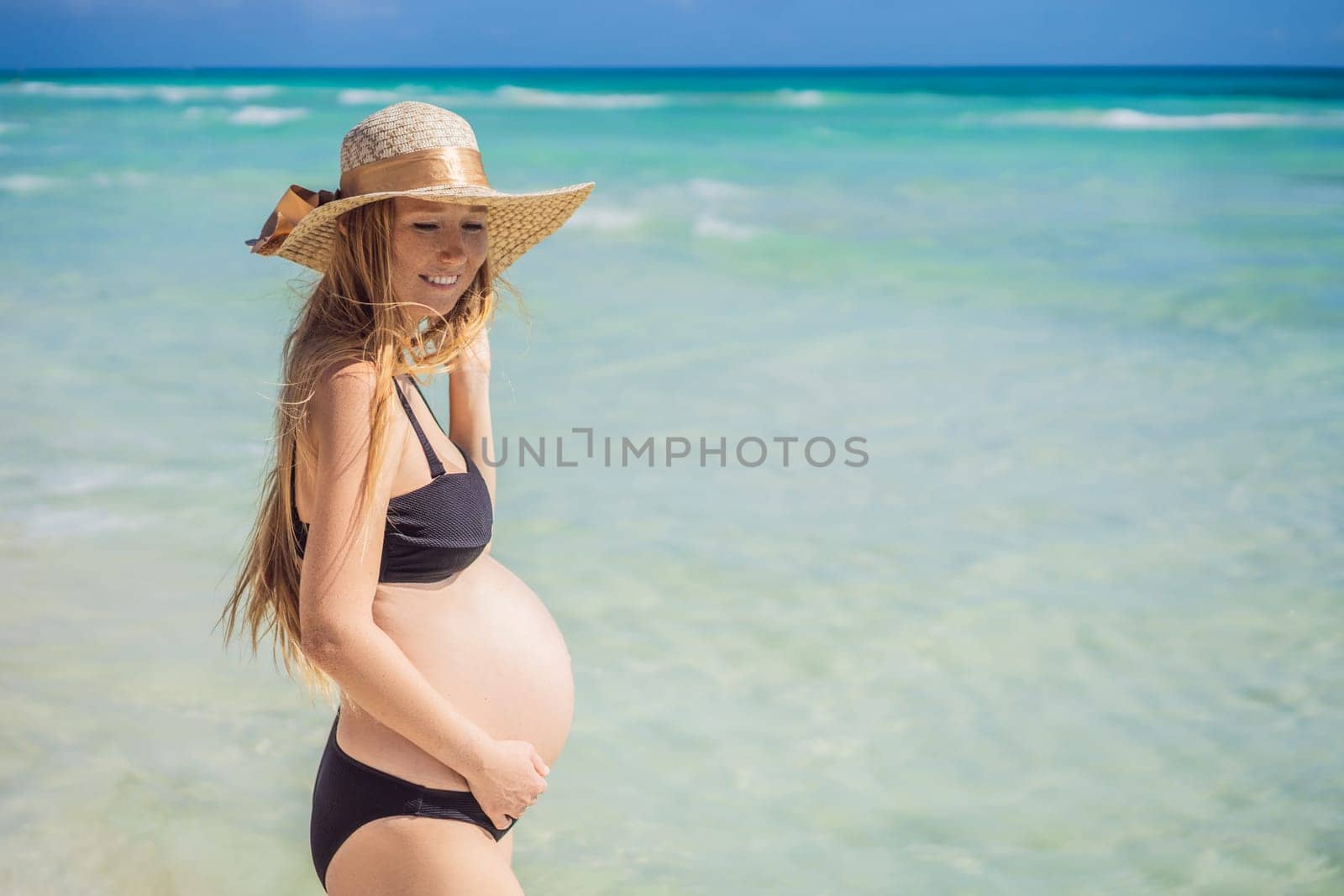 Radiant and expecting, a pregnant woman stands on a pristine snow-white tropical beach, celebrating the miracle of life against a backdrop of natural beauty.