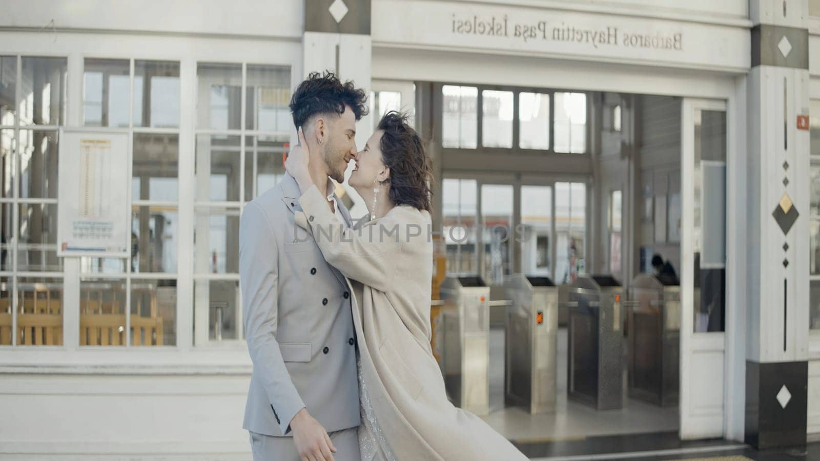 A young couple walking with an easy gait. Action.A girl in a coat with a beautiful short haircut and big earrings walks with her man in a suit and flirts with him. by Mediawhalestock