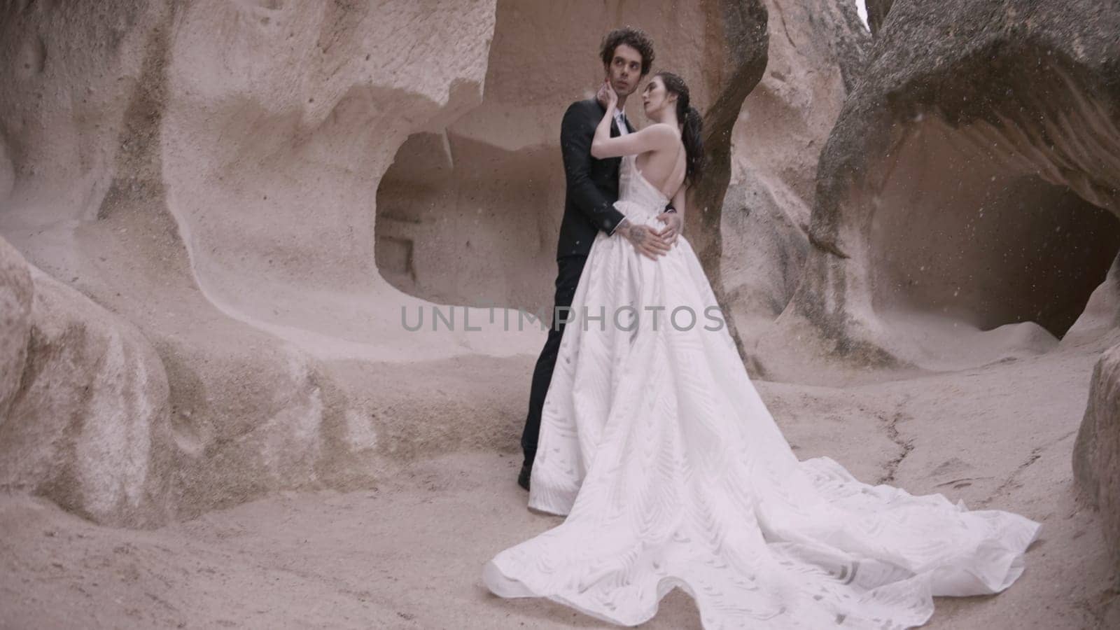 Beautiful bride and groom on background of rocks. Action. Newlyweds pose in natural landscape of rocks. Newlyweds embrace at rocky wall.