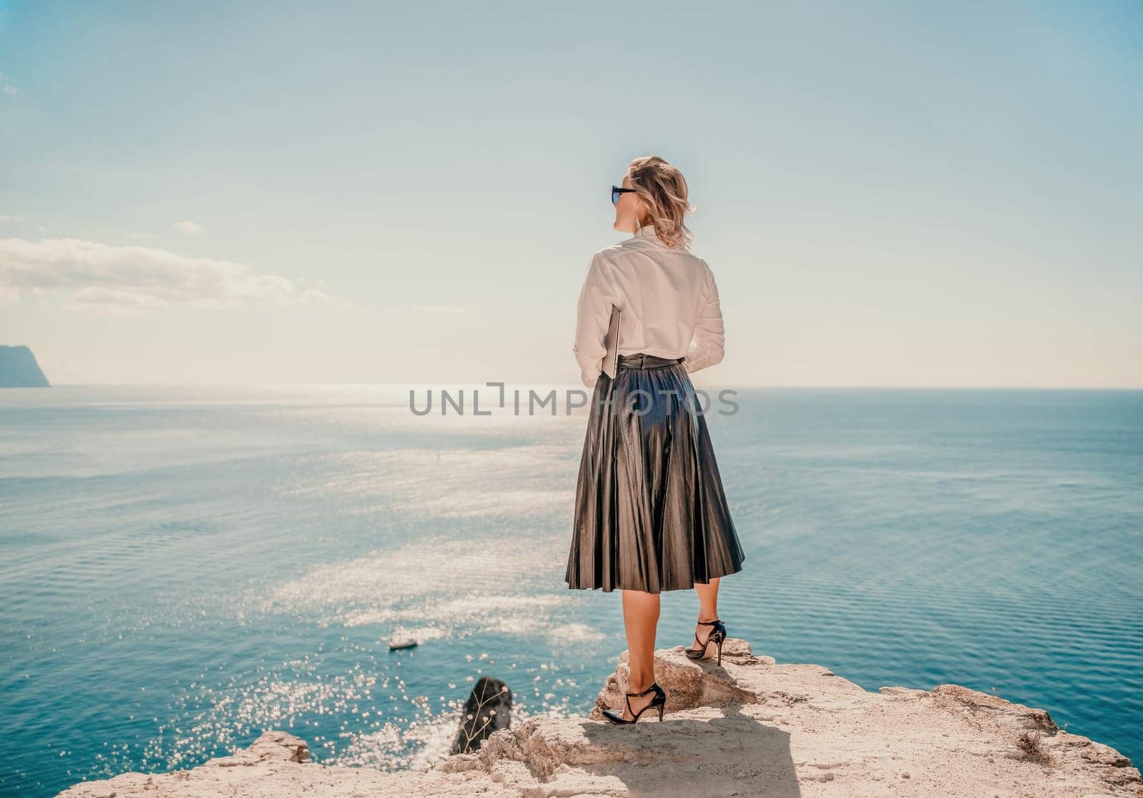 Freelance women sea working on a computer. Pretty middle aged woman with computer and phone outdoors with beautiful sea view. The concept of remote work. by Matiunina