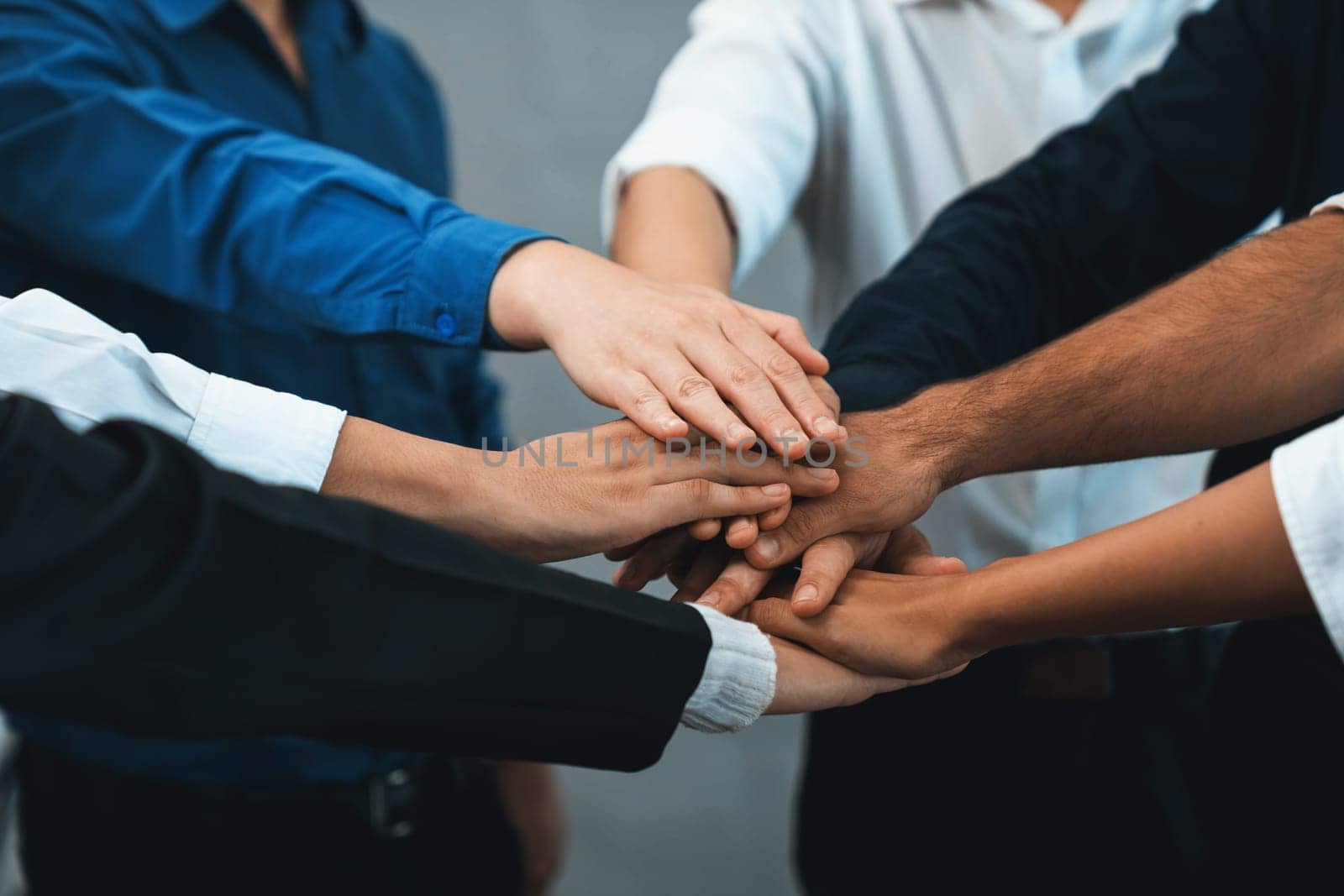 Group of diverse office worker join hand together in office room symbolize business synergy and strong productive teamwork in workplace. Cooperation and unity between business employee. Prudent