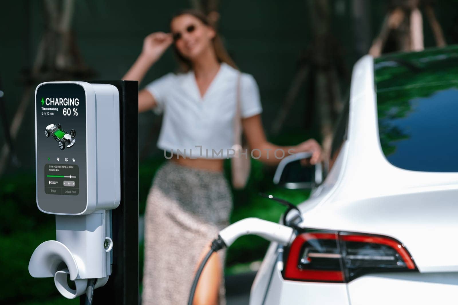 Young woman travel with EV electric car in green sustainable city innards by biancoblue