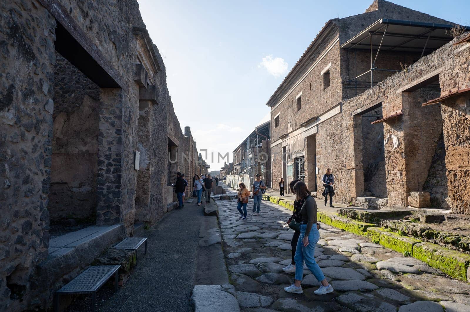 People walking through the Ancient Pompeii (UNESCO World Heritage Site). Paving stones of Via del Foro in November 2023. by martinscphoto