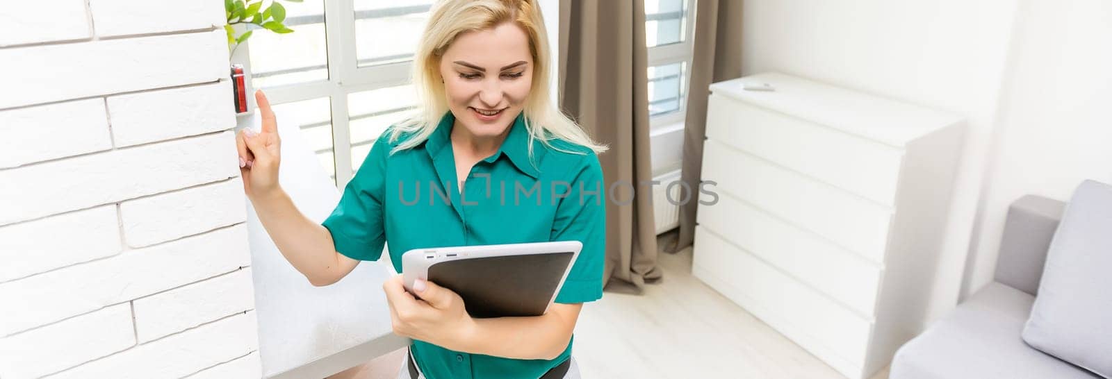 woman regulating heating temperature with a modern wireless thermostat installed on the white wall at home. Smart home heating regulation concept.