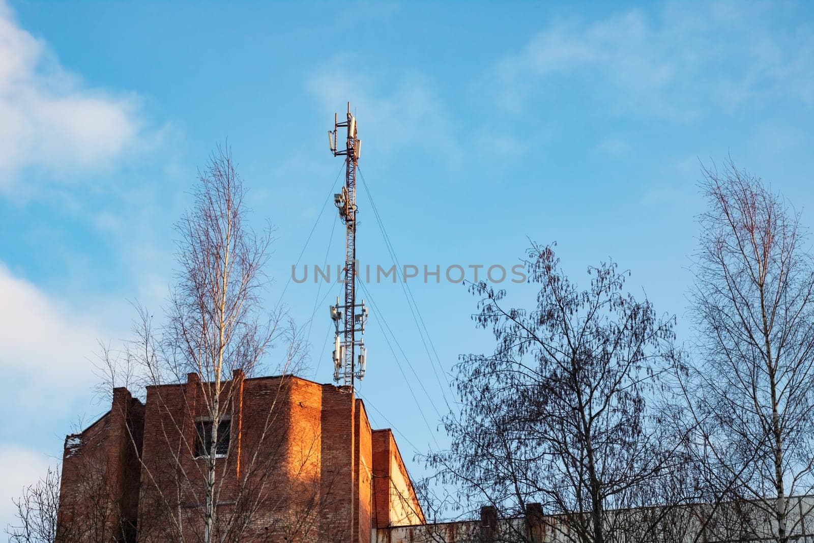 Communication antenna on the roof of a multistory building against the blue sky