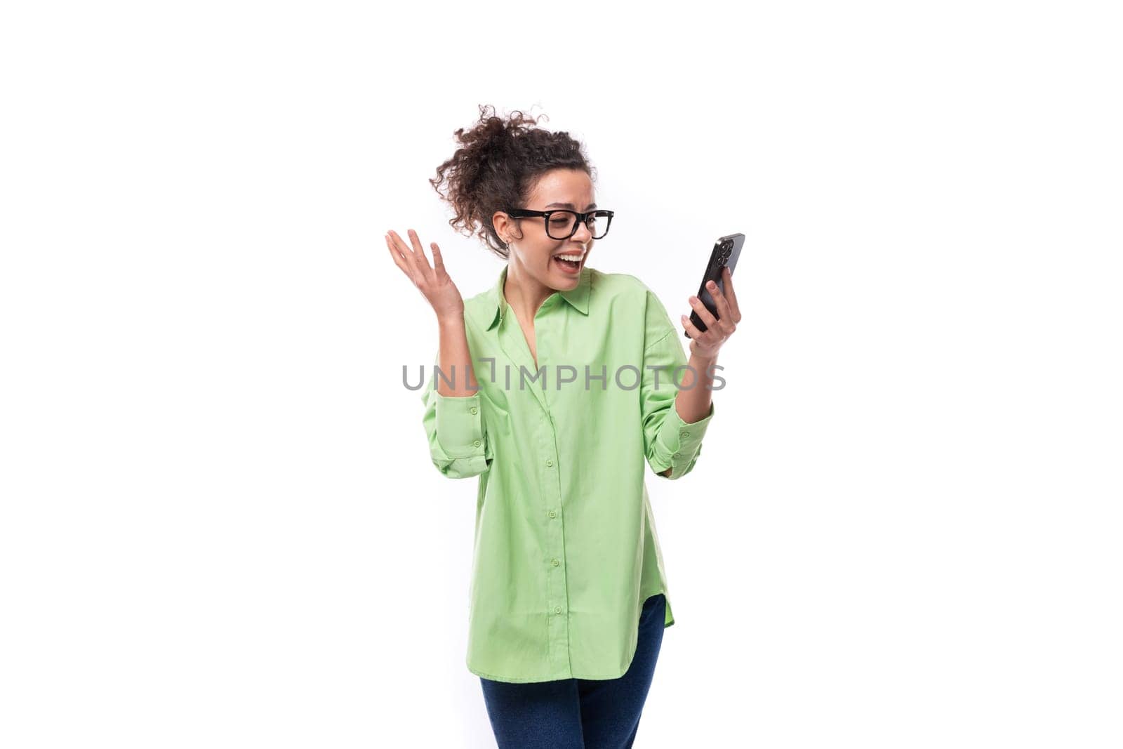 charming young slender female model dressed in a light green shirt chatting in a mobile phone on a white background. people lightstyle concept.