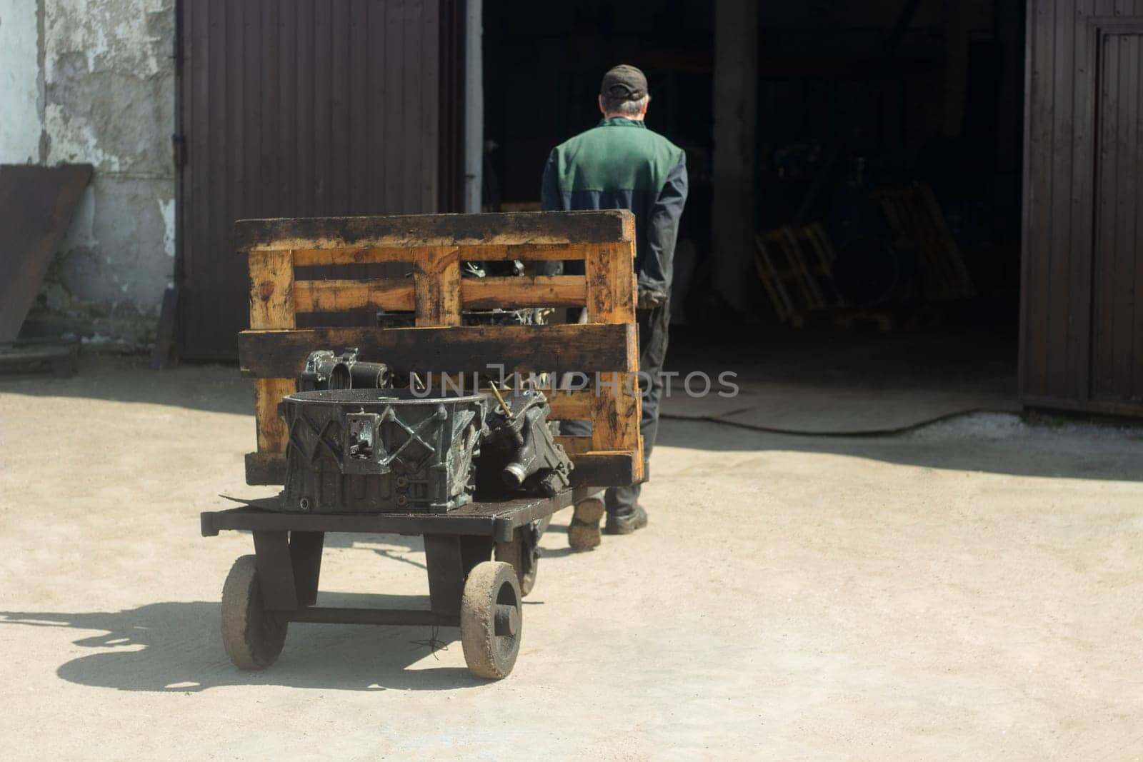 Man carries cart. Worker pulls load. Forklift on street. Man drags vehicle.