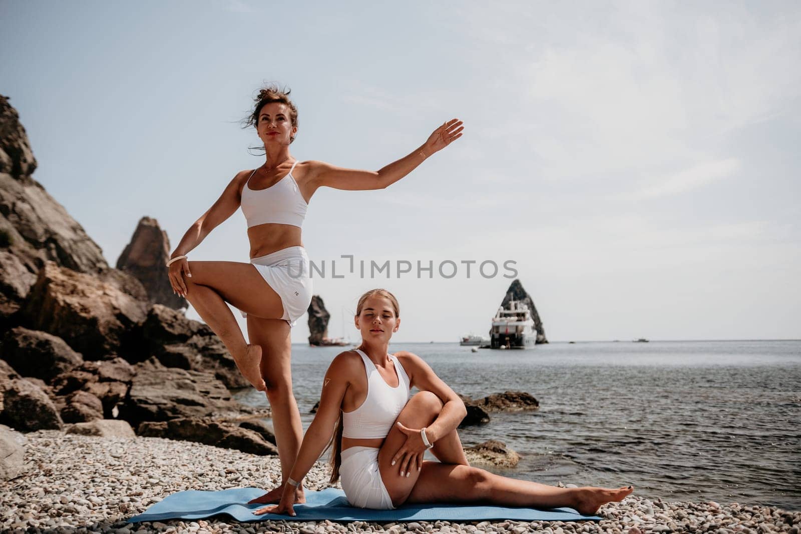 Woman sea yoga. Back view of free calm happy satisfied woman with long hair standing on top rock with yoga position against of sky by the sea. Healthy lifestyle outdoors in nature, fitness concept.