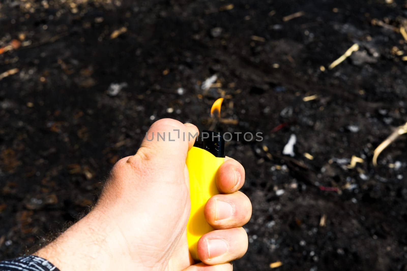 Burnt metal lighter in ashes. Consequences of fire. Close-up.