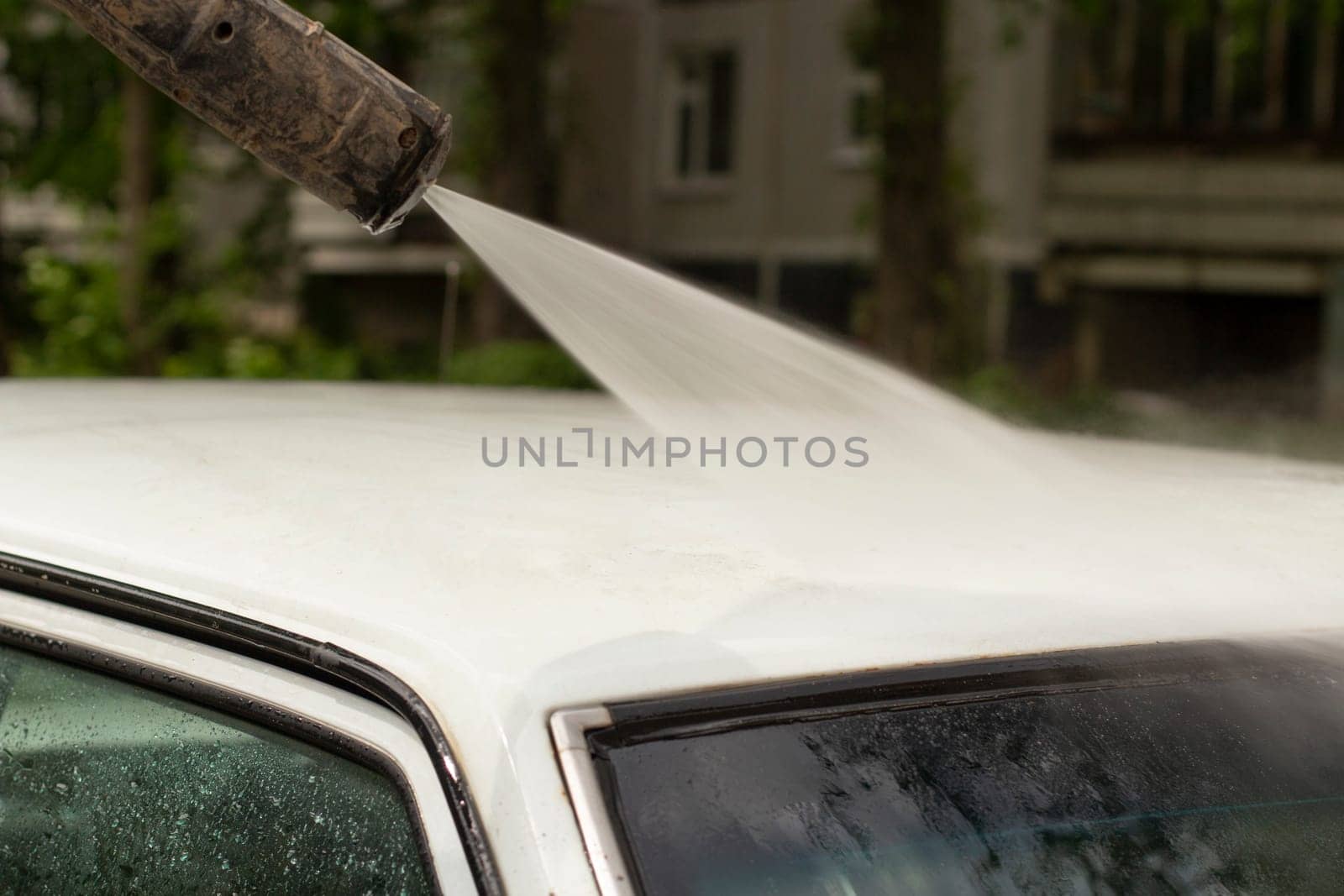 Wash car. Dirt laundering from machine. Water jet through transport. Work of car washer.