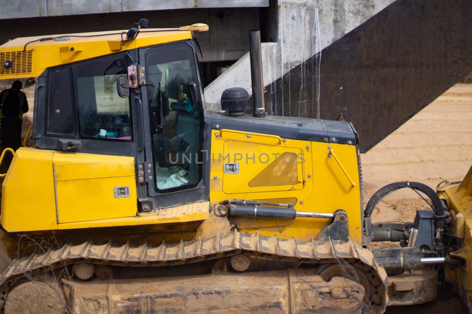 Construction site. Heavy machinery at the construction site. Construction among the sand. An excavator and a bulldozer level the site.