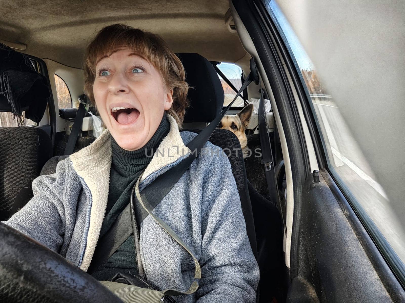 Terrified female driver a second before the accident. Scared middle-aged adult woman holds the steering wheel of a car. Frightened Lady girl who is owner or rent a car for travel by keleny