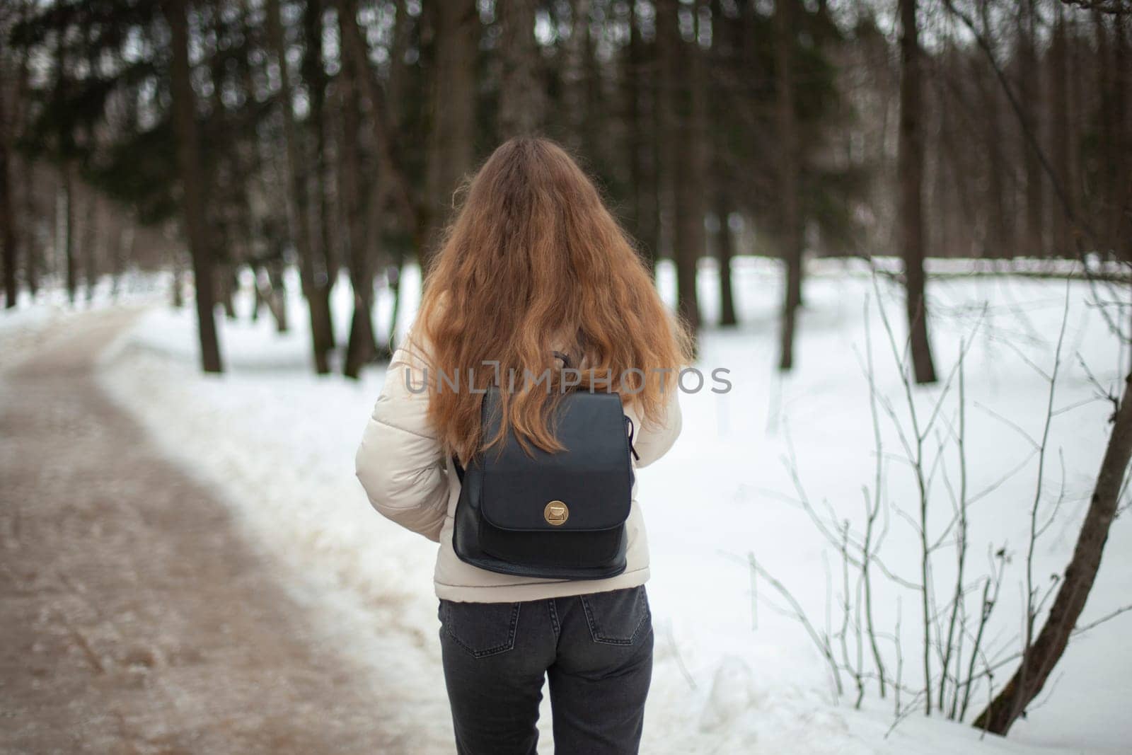 Girl walks down street in winter. Woman in winter in city. Bad road in yard in Russia. Student returns home.