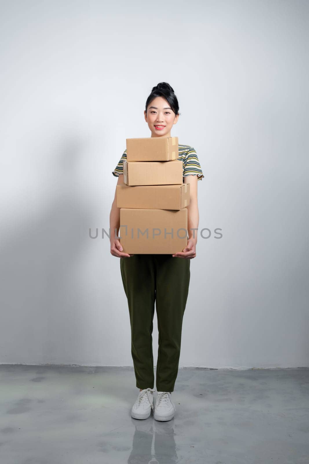 Happy Asian girl holding package parcel boxs isolated on gray background.